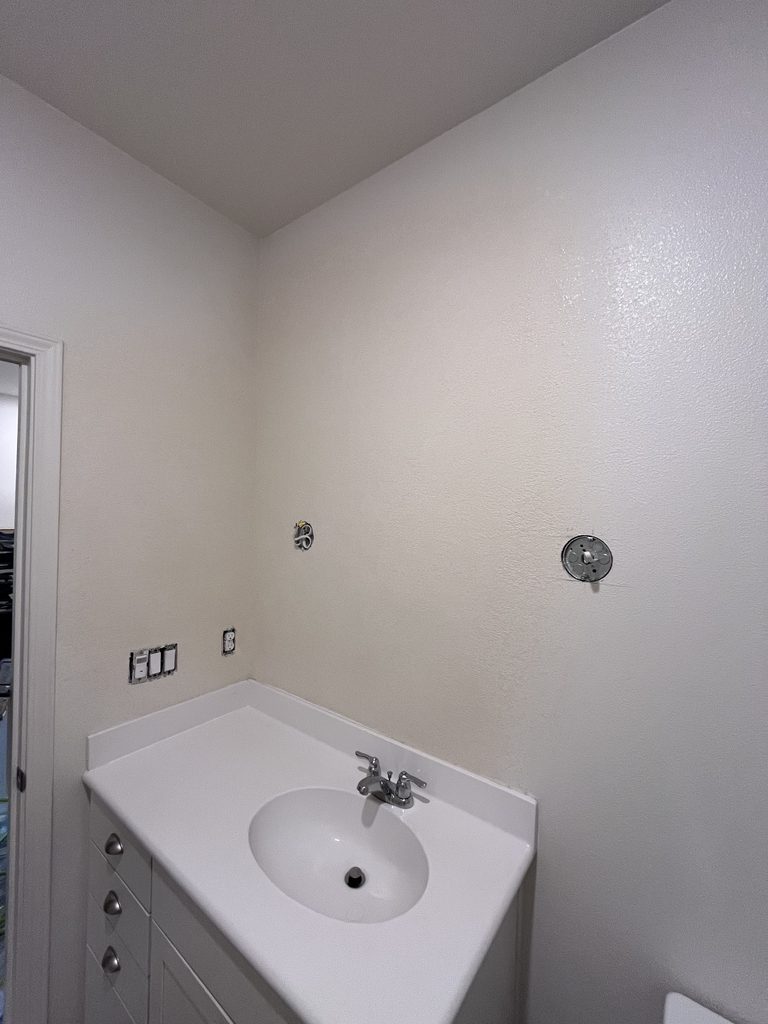 The same bathroom vanity wall after drywall repair, closed and textured to match the surrounding surface