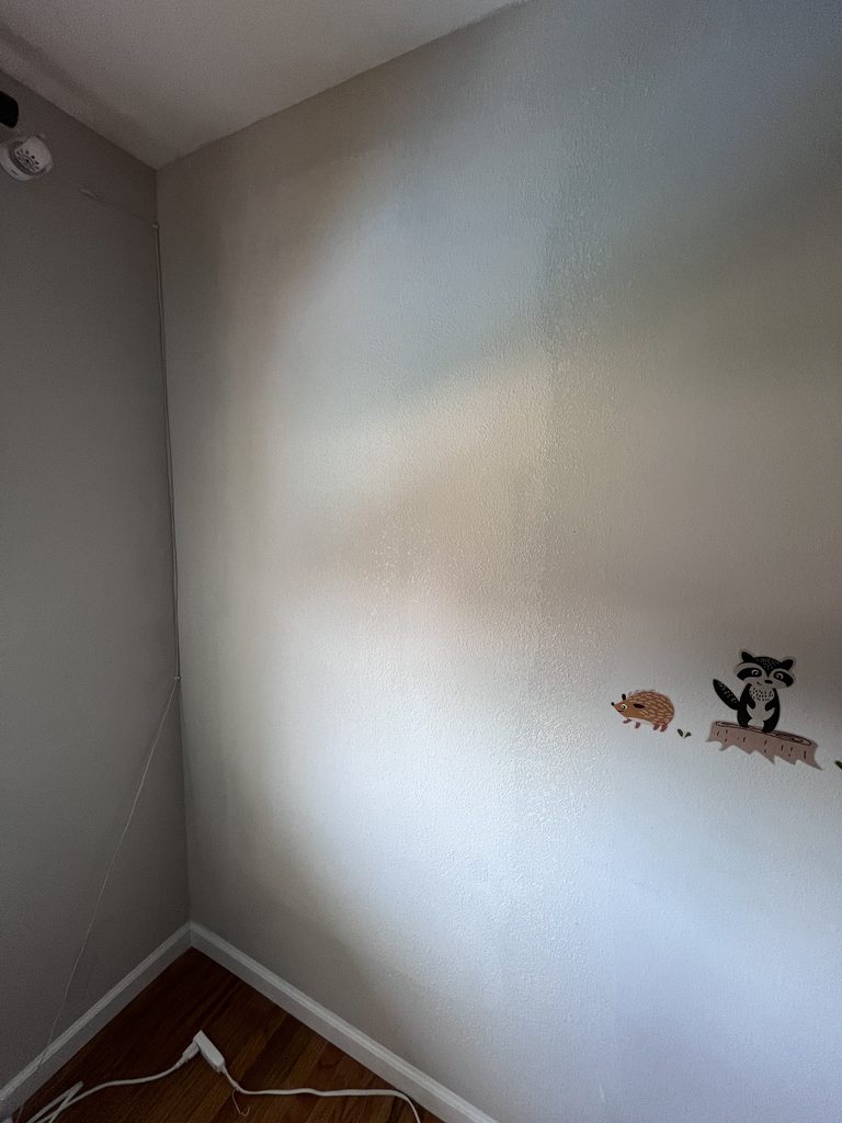 The same bedroom wall after drywall finishing, texture matched and blended so the repair is nearly invisible
