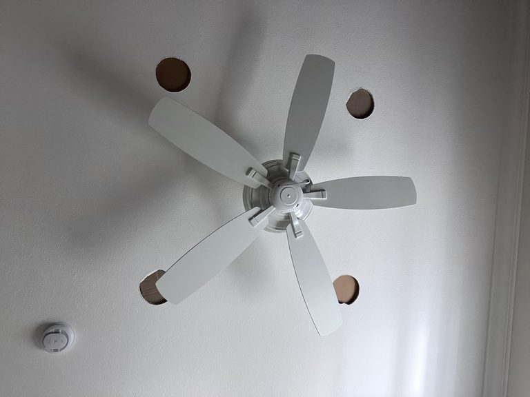 Ceiling openings cut around a ceiling fan for access before drywall patching